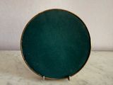 a green plate with a gold rim sitting on a marble table