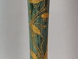 un vase vert orné de motifs dorés sur fond blanc