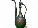 an old metal teapot with a bird on the top of it