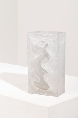 sculpture en bloc de marbre posée sur un socle blanc dans une pièce blanche