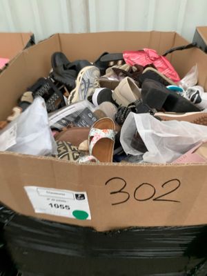 une boîte en carton remplie de chaussures posée par terre