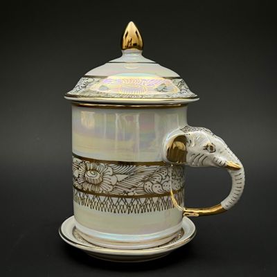 une tasse à café blanche et dorée ornée d'une tête d'éléphant