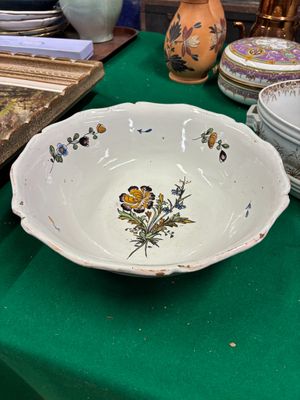 une table verte sur laquelle sont disposés des assiettes, des bols et des vases
