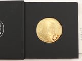 l'image d'une pièce d'or dans une boîte noire posée sur une surface blanche