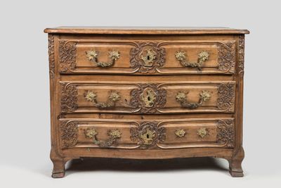 une commode ancienne ornée de sculptures raffinées et dotée de poignées en laiton