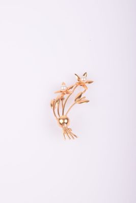un gros plan d'une broche en or représentant des fleurs sur fond blanc