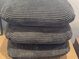 three grey knitted pillows stacked on top of each other