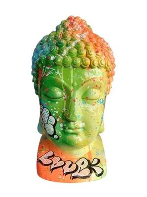 une statue représentant une tête de Bouddha sur laquelle on a tagué le visage