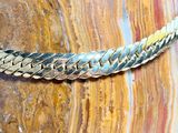 un gros plan d'un collier plaqué or posé sur un rocher