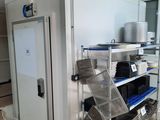 a kitchen with a refrigerator and shelves with pots and pans on it