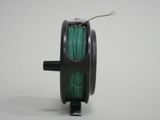a reel with a green thread on it on a white surface