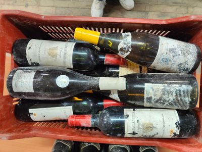 plusieurs bouteilles de vin dans un panier rouge posé sur une table