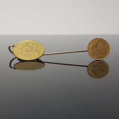 two gold coins sitting on top of each other on top of a table