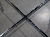 a metal table with a glass top on the floor
