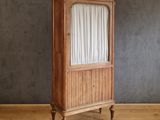 une vieille armoire en bois surmontée de rideaux, posée sur un parquet