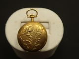 une photo en gros plan d'une montre de poche en or posée sur un socle en marbre