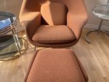 an orange chair and ottoman in front of a window in a living room