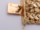 a close up of a gold plated necklace on a white surface