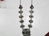 collier en argent orné de pierres multicolores, posé sur une table blanche