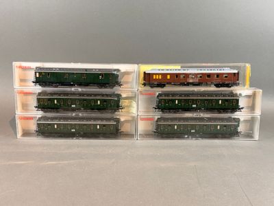 Deux trains miniatures sont posés dans des boîtes en plastique sur une table