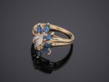 a gold ring with blue and white stones on a black surface