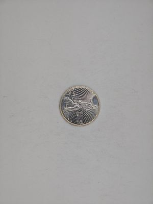 a silver coin with a bird on it on a white surface