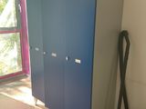 a blue cabinet in the corner of a room with a vacuum on the floor