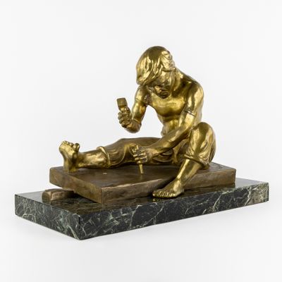 statue en bronze représentant un homme tenant un bébé dans ses bras, posée sur un socle en marbre