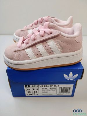 une paire de baskets Adidas roses et blanches dans une boîte bleue