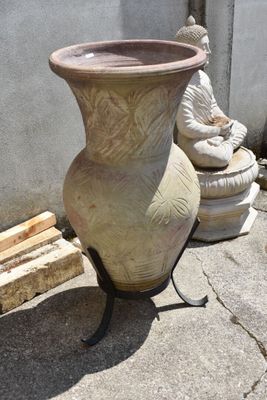 a large vase sitting on a stand next to a buddha statue