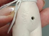 a small white figurine of a woman tied to a string