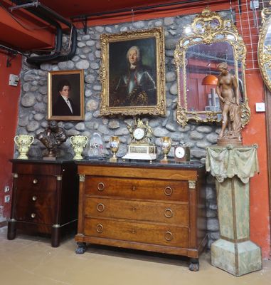 une pièce avec un mur en pierre, une commode, un miroir et une statue