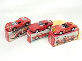 three red toy cars sitting on top of boxes on a white surface