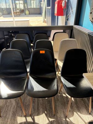 plusieurs chaises noires et blanches dans une pièce où se trouve une horloge accrochée au mur