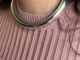 the woman is wearing a pink sweater and a silver necklace
