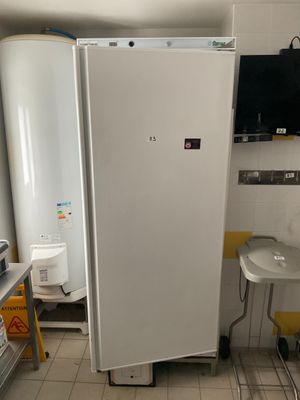 a white refrigerator in a kitchen with a tv on the wall