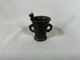 un vase noir contenant une cuillère, posé sur une surface blanche