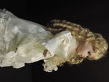 a doll with blonde hair and a white dress on a black background