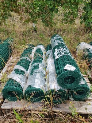 de nombreux rouleaux de fil de fer vert posés sur une palette dans l'herbe