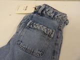 denim pants with a braided pocket on a white table