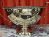 a silver bowl on a marble table with a red curtain in the background