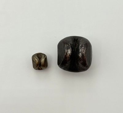 deux morceaux de pierre noire posés l'un à côté de l'autre sur une surface blanche