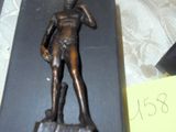 une statue en bronze représentant un homme debout sur une table