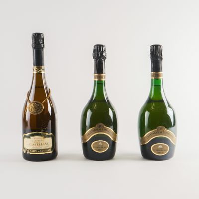 trois bouteilles de champagne posées les unes à côté des autres sur une surface blanche