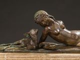 bronze statue of a woman laying on her stomach with a dog