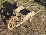 a wooden wheelbarrow sitting on the ground in the grass