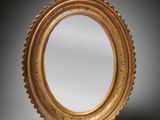 an oval mirror with a gold frame on a gray background