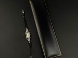 une montre et un stylo posés sur une surface noire
