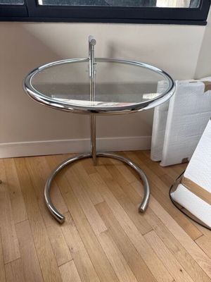 une petite table avec un plateau en verre posée sur un parquet en bois massif