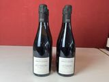 Deux bouteilles de vin sont posées sur un comptoir devant un mur rouge.